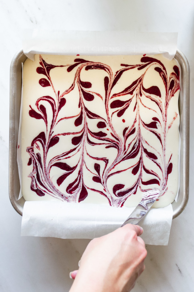 Swirling cherry sauce into cheesecake batter to create a pattern